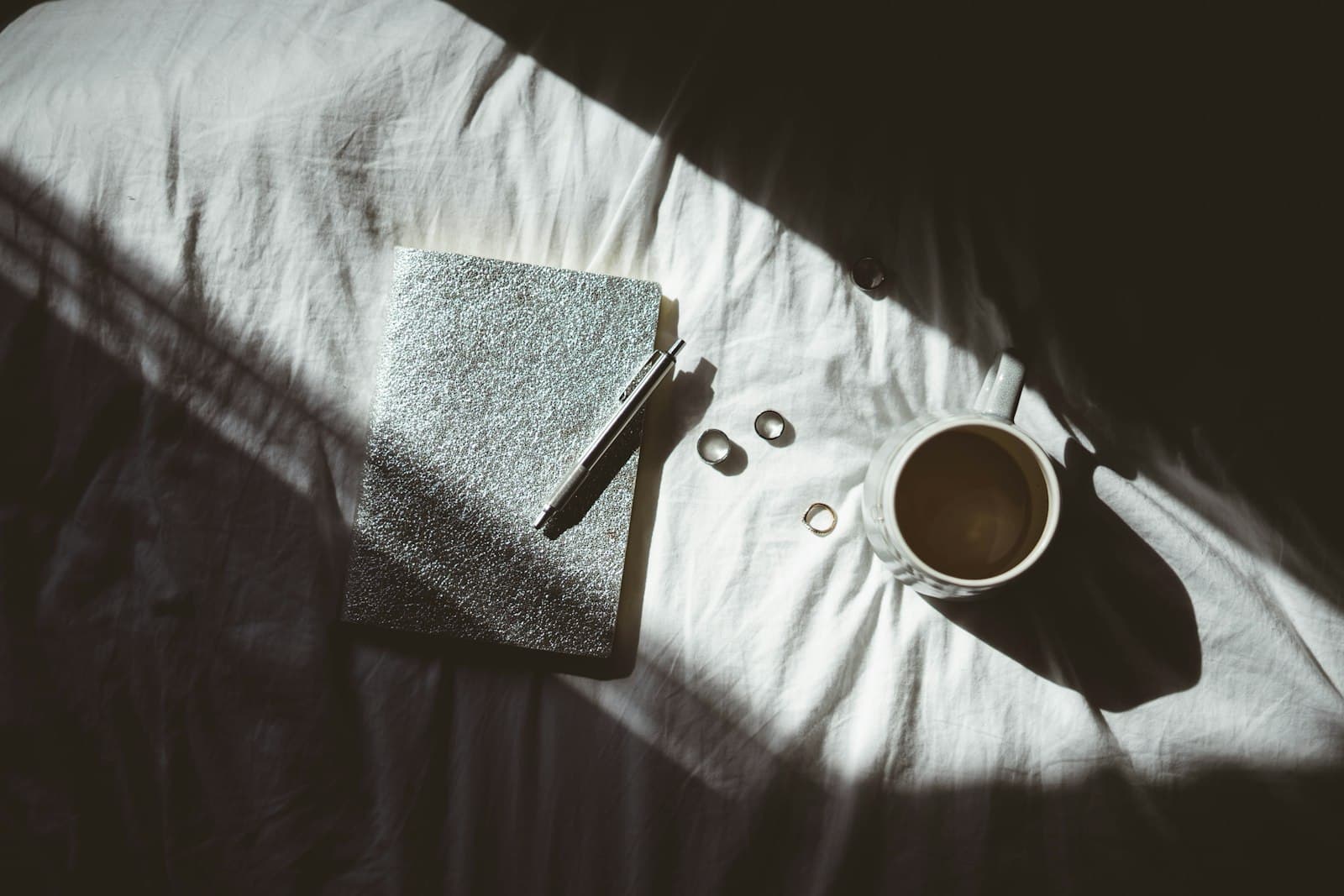 A cup of coffee and a book on a bed
