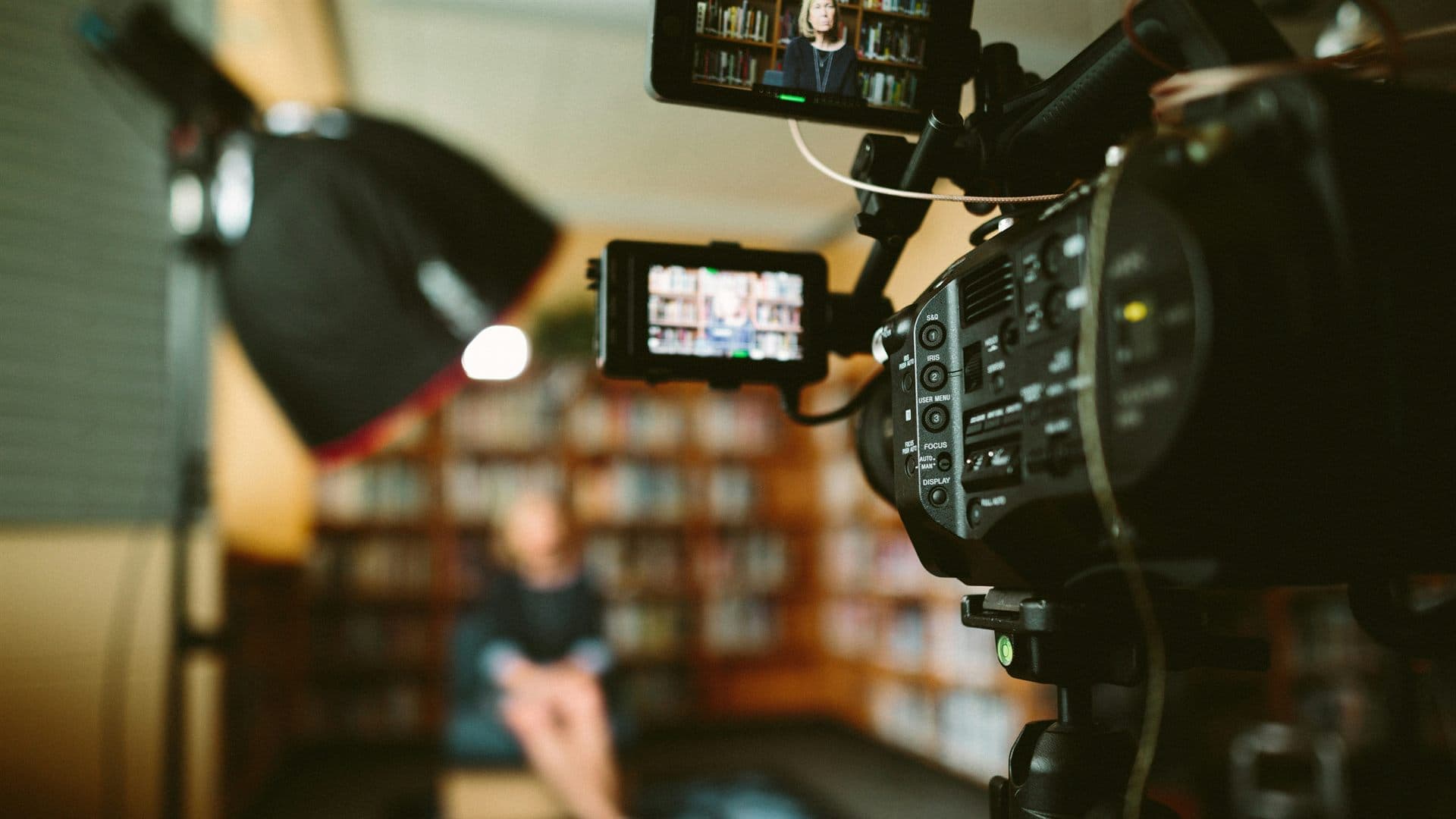 A video camera filming an interview among bookshelves